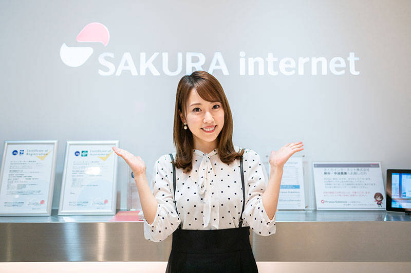 さくらインターネットのロゴ前で写真を撮る福原香織さん