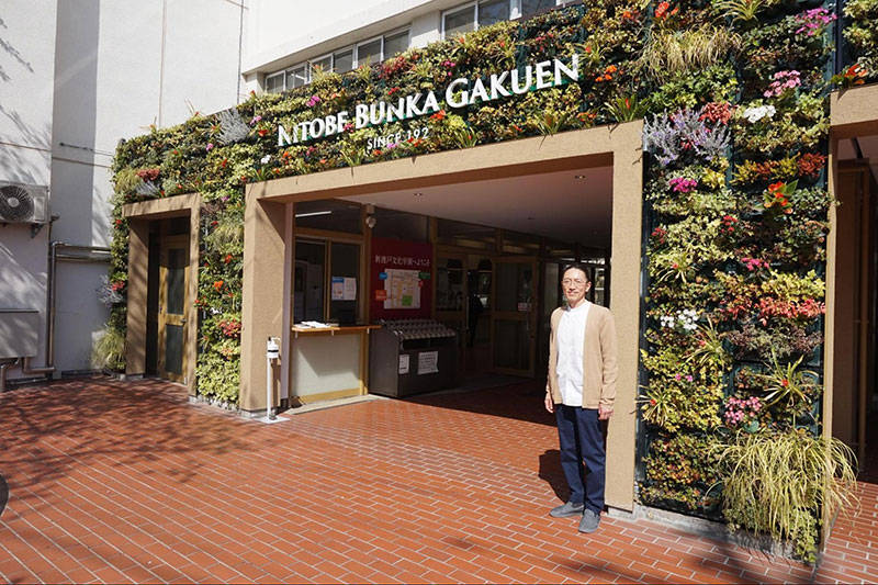 新渡戸文化学園の正門前で。アーチには季節の花が咲いている。